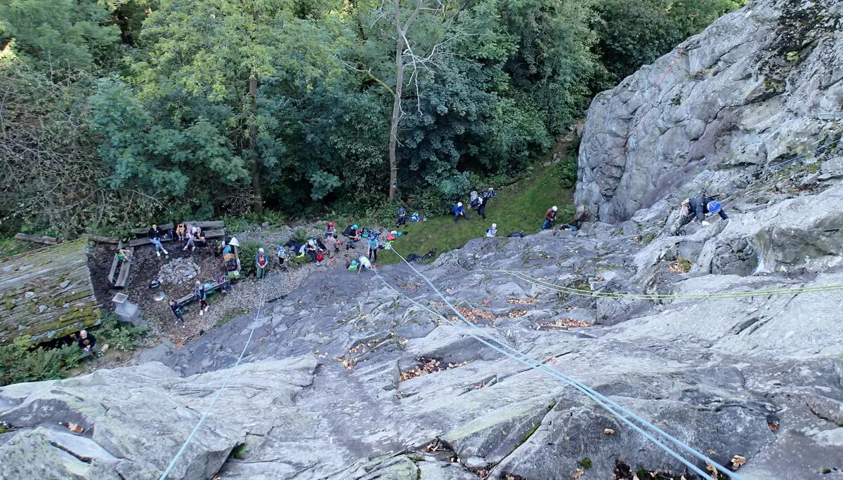 Lange Seile hängen eine Felswand herunter, unten stehen Kletterer | © Christine Eyle